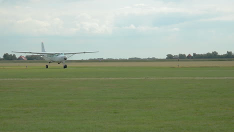 A-small-aircraft-with-open-door-is-taxiing-on-the-runway-and-passes-two-parked-cesna-airplanes