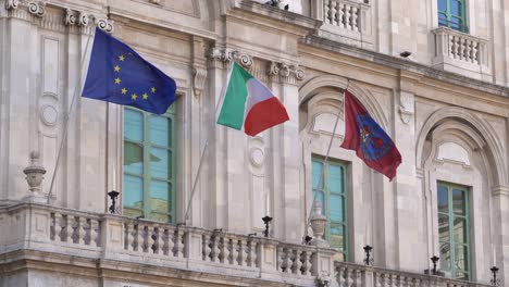 Las-Banderas-De-La-Unión-Europea,-Italia-Y-La-Universidad-De-Catania-Ondeando-En-El-Viento-En-El-Edificio-De-La-Universidad