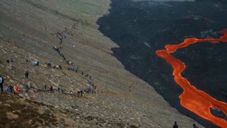 A-Trail-Of-People-Watching-The-Flowing-Volcanic-Lava-From-Fagradalsfjall-Volcano-In-Iceland---aerial-shot