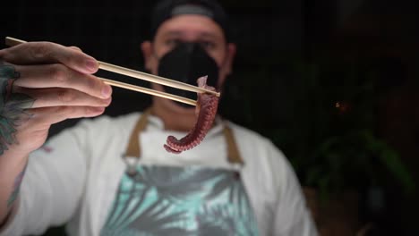 Latin-Chef-holding-octopus-with-chopsticks-for-recipe-sushi
