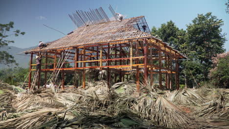 Vietnamesische-Männliche-Bauarbeiter-Bauen-Ein-Traditionelles-Holz--Und-Palmenhaus