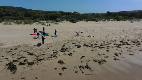 Los-Niños-En-La-Clase-De-Surf-Australiano-Caminan-Hacia-La-Playa-De-Arena-Para-Tomar-Un-Descanso