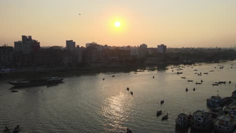Buriganga-river-port-beside-urban-city-in-sunrise-with-boats---aerial-establishing-drone-flight-shot