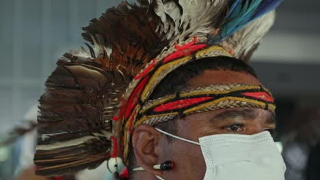 Indigener-Stammesmann,-Der-Einen-Traditionellen-Kopfschmuck-Aus-Dem-Amazonas-Regenwald-Und-Eine-Gesichtsmaske-Zum-Schutz-Vor-Covid-Trägt