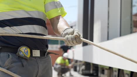 Trabajador-Del-Sitio-De-Construcción-Tirando-De-La-Cuerda-Con-Guantes-Y-Ropa-De-Alta-Visibilidad