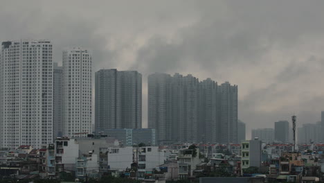 Atmospheric-shot-of-urban-area-with-large-high-rise-apartment-buildings-with-fasst-moving-morning-fog,-clouds-or-pollution