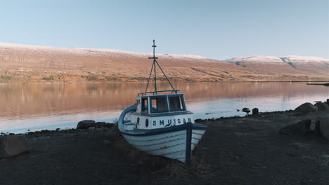 Static-shot-of-small,-abandoned-fishing-boat-on-beach-in-Akureyri-Iceland