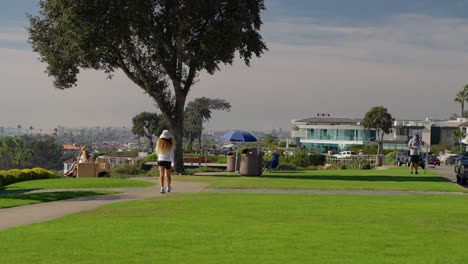 Caucasian-lady-walking-on-a-sidewalk-in-a-roadside-park