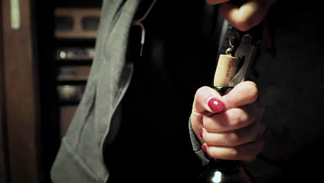 Woman-with-red-nail-polish-pulling-cork-out-of-wine-bottle
