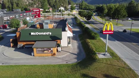 Restaurante-Mcdonalds-Y-Cartel-A-Lo-Largo-De-La-Carretera-Noruega---Antena-En-Movimiento-Hacia-Atrás-Al-Atardecer-De-La-Tarde