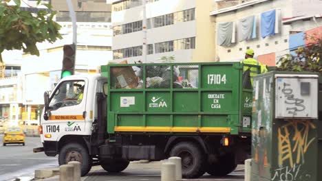 Sanitary-workers-ride-on-a-garbage-truck,-collecting-garbage-in-the-city-in-Via-España-,-Panama