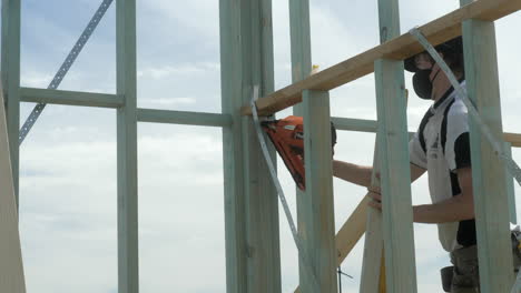 Apprentice-Carpenter-Uses-Nail-Gun-To-Fasten-Timber-Housing-Frame