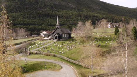 Norwegian-Landscape-With-Old-Wooden-Church-And-Graves-In-Sel,-Norway---aerial-drone-shot
