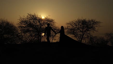 Aerial,-edited---Silhouette-of-a-couple-giving-each-other-a-high-five-celebrating-successful-climb-on-the-mountain-in-beautiful-sunset