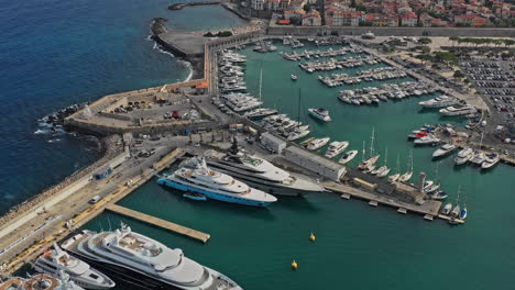 Antibes-France-Aerial-v42-birds-eye-view-dolly-in-shot-overlooking-at-yachts-docked-at-port-vauban,-toward-secluded-la-gravette-beach-alongside-with-downtown-residential-houses---July-2021