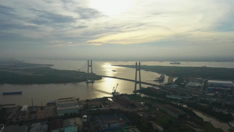Fly-in-over-urban-area-towards-river-and-large-modern-suspension-bridge-in-early-morning-light-part-three