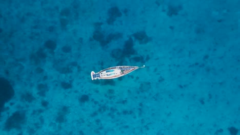 Yacht-swaying-and-bobbing-in-the-ocean-revealing-reef-in-the-clear-blue-waters