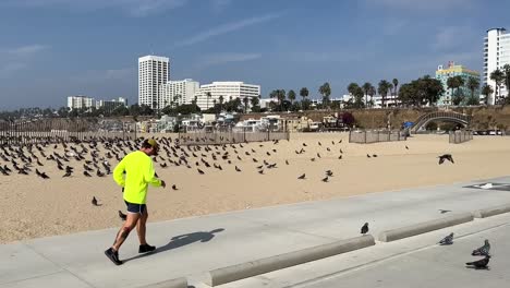 Entschlossener-Männlicher-Läufer-Beim-Morgendlichen-Joggen-Entlang-Des-Ruhigen-Strandwegs,-Santa-Monica,-USA,-Kamerafahrt