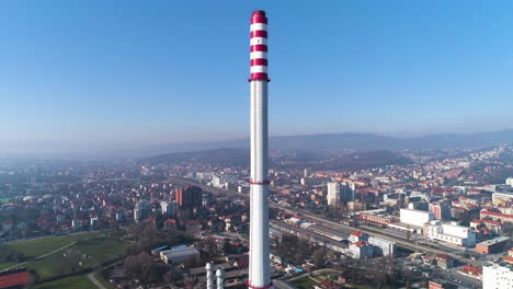 Vista-Aérea-De-La-Chimenea-De-La-Central-Eléctrica-Con-Zagreb,-Croacia-En-Segundo-Plano.