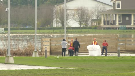 Group-of-workers-prepares-huge-white-bag-for-helicopter-pick-up-transportation,-handheld-view