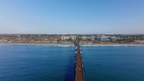 people-walk-along-huge-wooden-pier-of-Oceanside-beach-town,-in-San-Diego-county,-CA