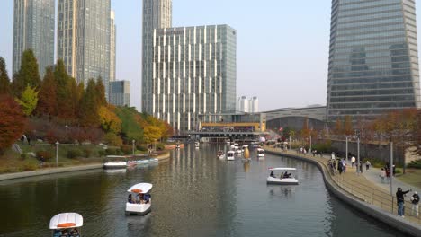 La-Gente-Viaja-En-Botes-Familiares-De-Remo-Y-Botes-Lunares-En-El-Parque-Central-De-Incheon-Songdo---En-El-Lago-Y-Pasea-Por-Pasarelas-Con-Máscaras-Durante-Covid-19-En-Otoño,-Corea-Del-Sur