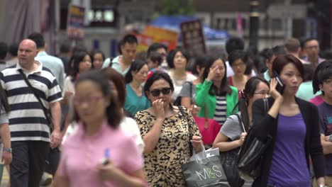 Close-up-of-a-car-crossing-the-camera-field-while-several-Chinese-nationals-walk-along-the-street