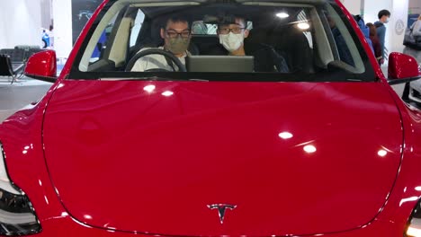 Visitors-sit-and-test-an-American-EV-electric-company-car-Tesla-Motors-car,-Tesla-Model-Y,-during-the-International-Motor-Expo-in-Hong-Kong