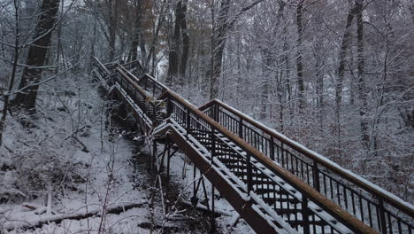 Light-snow-falling-in-a-wide-establishing-shot-looking-up-at-a-snow-covered-staircase-in-Glen-Stewart-Ravine