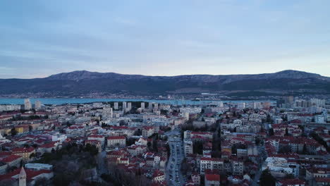 Vibrant-city-of-Split-with-massive-mountain-range-in-background,-aerial-drone-shot