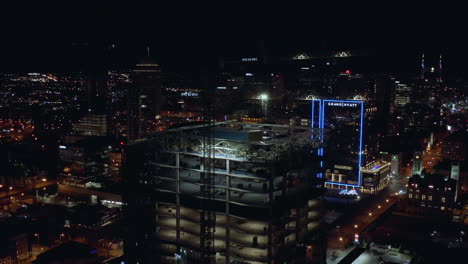 Antena-Nocturna-De-La-Torre-De-Construcción-En-Construcción-Con-Grúas-En-La-Parte-Superior,-Drone-4k