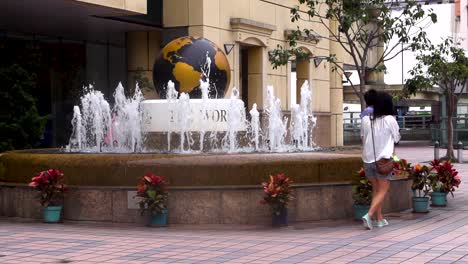 Mother-with-her-child-stand-in-front-of-a-water-fountain-in-the-city-center