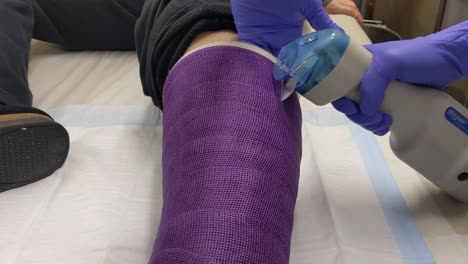 A-gloved-orthopedic-nurse-cuts-through-the-outside-of-a-left-leg-cast-for-removal