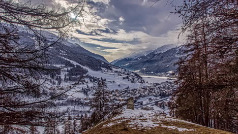 Majestic-time-lapse-of-clouds-in-motion-over-beautiful-snow-covered-village-in-valley-surrounded-by-mountains---Bormio,Italy