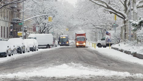 Trucks-And-Cars-Move-Slowly-Down-Avenue-In-New-York-City-During-Snowfall