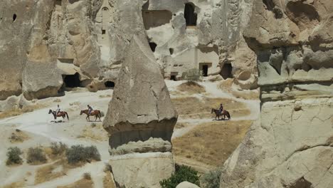 Riders-with-horses-walking-through-the-tufa-landscape-of-the-UNESCO-World-Heritage-Site-Goreme,-Cappadocia,-central-Anatolia,-Turkey,-Asia