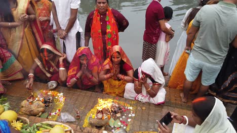 View-of-the-Indian-people-doing-rituals-during-Hindu-wedding-with-fruits,-fire,-flowers-in-front-of-ganga-river-water