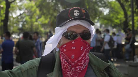 Un-Veterano-De-La-Guerra-De-Guerrillas-Usa-Un-Sombrero-Che-Guevara-Y-Un-Pañuelo-Rojo-Para-Cubrirse-La-Cara-Durante-Una-Protesta-Pacífica-Contra-Las-Políticas-Del-Actual-Presidente-Nayib-Bukele---Cámara-Lenta