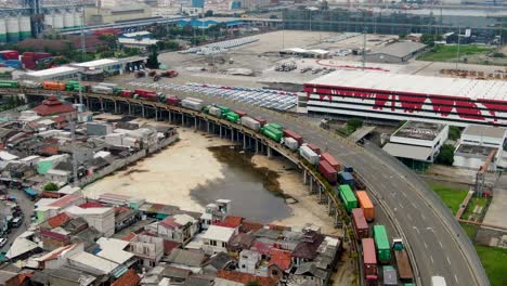 Massiver-Sattelschlepper-Stau-In-Jakarta-Zwischen-Fabriken-Und-Slums,-Drohnenaufnahme-Aus-Der-Luft