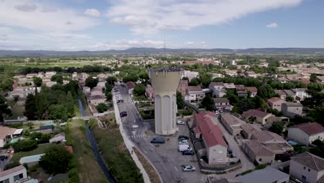 Water-tower-with-antennas-near-homes-and-buildings,-Aerial-dolly-out-shot