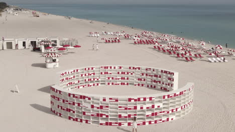 Aerial:-Red-and-white-art-installation-matches-beach-chairs,-umbrellas