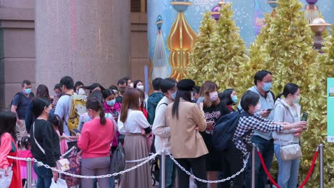Vor-Einem-Einkaufszentrum-In-Hongkong-Stehen-Menschen-Schlange,-Um-Zugang-Zu-Einer-Weihnachtlichen-Installationsveranstaltung-Zu-Erhalten