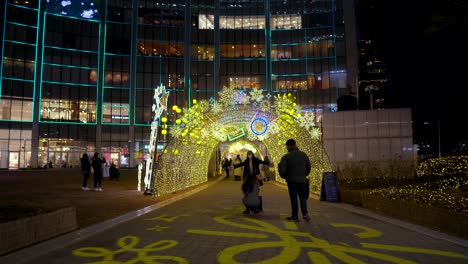 People-enjoying-the-holiday-decorations-and-sparkling-lights-at-the-Lotte-World-Tower-in-Seoul,-Korea-at-night-wearing-face-masks-2021