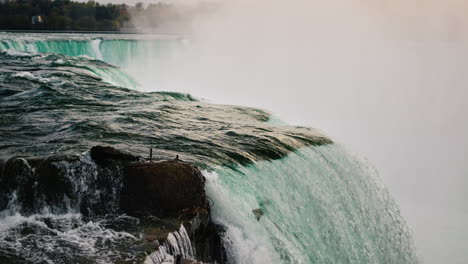Die-Berühmten-Niagarafälle,-Weit-Unten-Fährt-Ein-Schiff-Mit-Touristen.-Sehenswürdigkeiten-Von-Amerika.-4K-Video-In-Zeitlupe