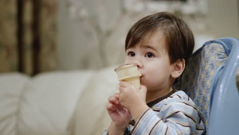 Two-years-old-Asian-baby-eats-ice-cream,-sits-in-a-child-seat-for-feeding.-Side-view