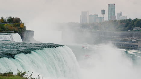 Die-Berühmten-Niagarafälle,-Im-Hintergrund-Sind-Gebäude-An-Der-Kanadischen-Küste-Zu-Sehen