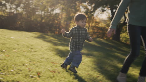 A-happy-two-year-old-kid-happily-runs-to-his-mother.-On-a-green-meadow-in-the-rays-of-the-setting-sun