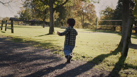 Happy-Asian-toddler-running-along-farm-fence.-Handheld-shot