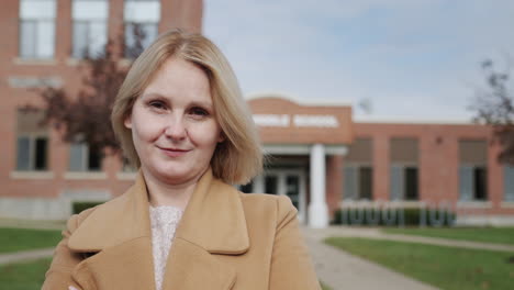 Portrait-of-a-female-teacher-against-the-background-of-an-elementary-school-building-in-the-United-States