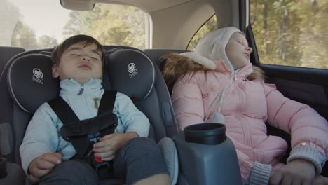 Sleeping-children-drive-in-the-back-seat-of-the-car.-Asian-baby-sleeps-in-a-child-car-seat,-a-girl-naps-next-to-her.